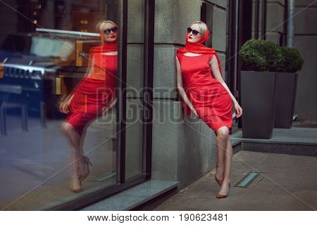 Fashionable woman admires herself in the reflection of the shop window.