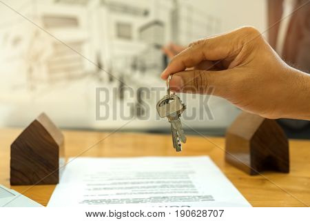 Real estate conceptSales are selling homeholds the house key in hand with house model.