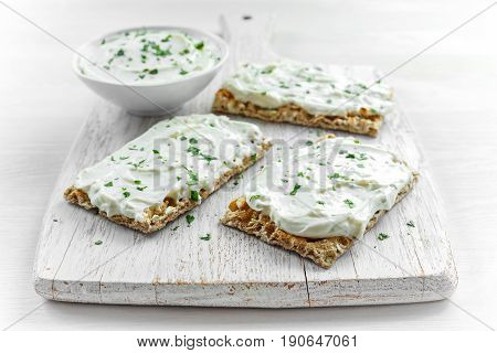 Homemade Crispbread toast with Cream Cheese and parsley on white wooden board background