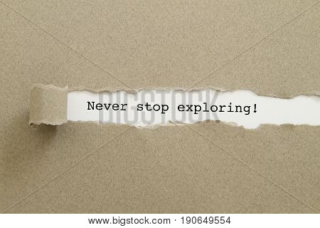 Never stop exploring word written under torn paper concept .