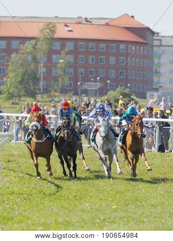 STOCKHOLM SWEDEN - JUNE 06 2017: Tough fight between colorful jockeys riding gallop arabian race horses at Nationaldags Galoppen at Gardet. June 6 2017 in Stockholm Sweden