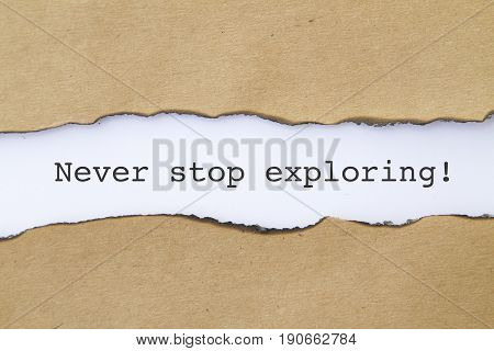 NEVER STOP EXPLORING word written under torn paper .