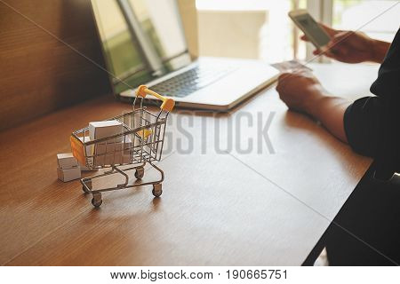 Internet online shopping concept with laptop and shopping-cart.Vintage tone retro filter effect soft focu.selective focus