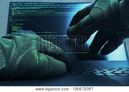 Hacker hands wearing gloves working on a console commands. Internet cyber concept. Green toning.