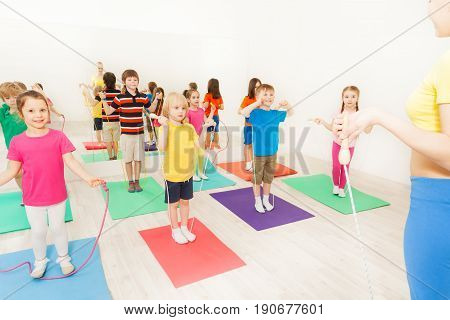 Sports coach teaching kids jumping with skipping rope in gym