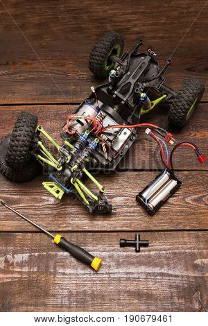 Dismantled broken Rc radio control car crawler model toy repair. Green toy suv in repairshop workplace, top view