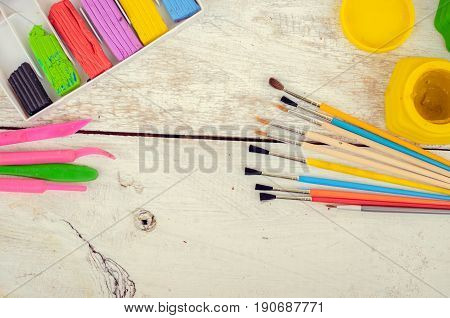 Tools for creative work on a white wooden background. Watercolor paintbox. Color paints with paint brushes and plasticine. Back to school. Kids painting concept. Children art. Top view. Copy space.