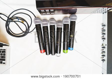 Top view of six black wireless professional microphones prepared for leading or musicians on a white background, isolate. Sound equipment for entertainment and performances by artists.