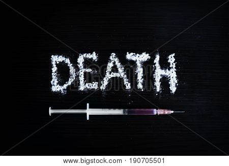 inscription death cocaine accented by a syringe of heroin on a black background