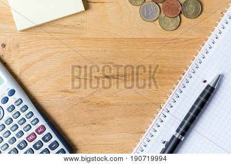 Work desk with note pad calculator and biro on wooden table from above