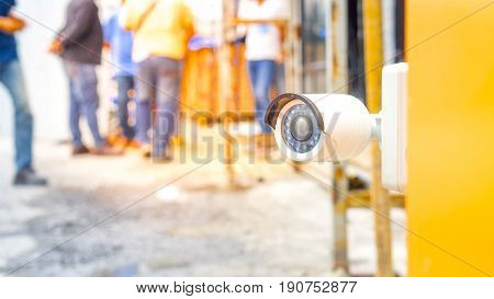 Surveillance camera and security concept - Close up Surveillance cctv camera on gate of construction site people with flare light effect and copyspace