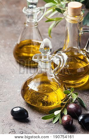 Olive oil in a glass bottle and olive branch on brown stone table