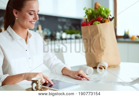 Young woman planning expenses and paying bills on her kitchen
