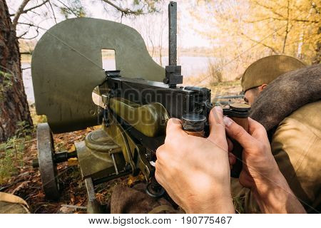 Dyatlovichi, Belarus - October 1, 2016: Reenactors Dressed As Russian Soviet Red Army Soldiers Of World War II Hidden Sitting With Maxim's Machine Gun Weapon In An Ambush In Autumn Forest.