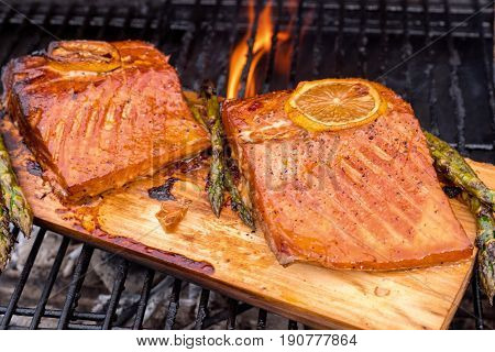 cedar plank salmon with lemon cooking on grill