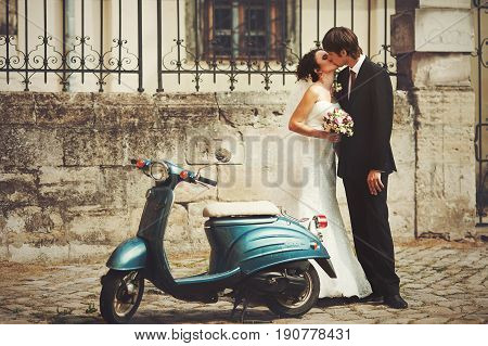Goom Kisses A Bride Standing Behind A Blue Scooter