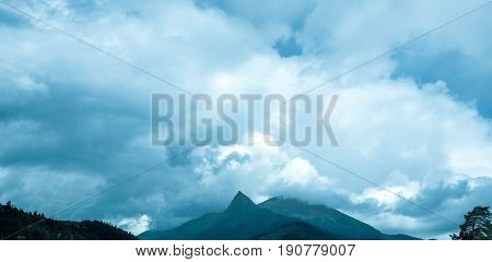 Blue sky in front of a thunderstorm. The pumping atmosphere. Rain clouds. Mountains on the horizon