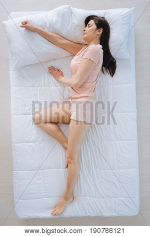Everyone needs rest. Attractive nice pleasant woman sleeping and having dreams while lying comfortably on her bed