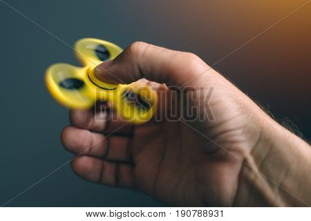 Yellow fidget spinner in male hand selective focus