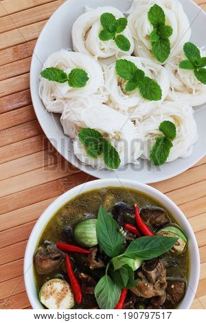 Thai-rice-flour noodles (kanom Jeen) arranged with green curry on brown wood floor