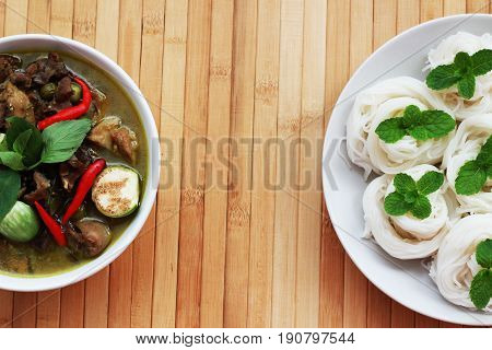 Thai-rice-flour noodles (kanom Jeen) arranged with green curry on brown wood floor