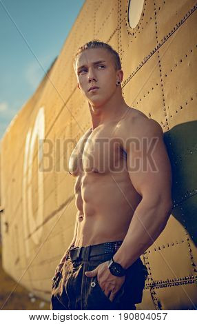 A handsome guy is standing by the plane.