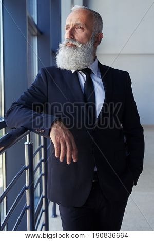 Vertical of thoughtful man with grey beard looking out window