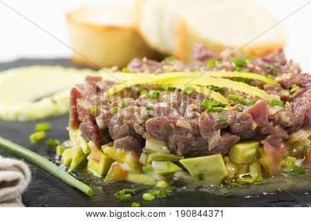 Bluefin Tuna Tartare On A Black Slate Plate With Avocado.