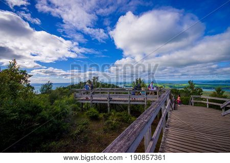 AUCKLAND, NEW ZEALAND- MAY 12, 2017: Unidentified people enjoying the beautiful view from top in the mountain in Rangitoto Island walking in wooden paths, New Zealand in a sunny day.
