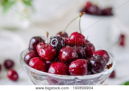 Close Up Fresh Cherry Fruit In Glass Vase, Other Dishes With Berries And Jar With Jasmine And Wildfl