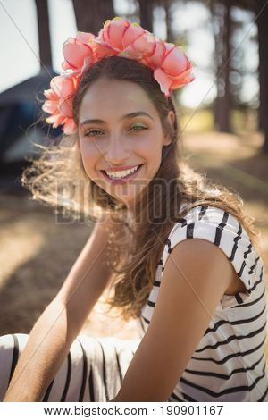 Portrait of smiling woman sitting on field while camping at forest