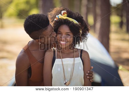 Close up of romantic couple sitting against tent on field
