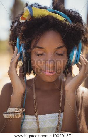 Close of young woman with eyes closed listening music at campsite
