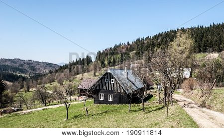 hamlets with wooden houses on settlement Mrackov bellow Jakubovsky vrch hill in spring Javorniky mountains in Kysuce region in Slovakia during spring day with clear sky