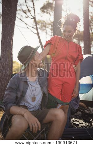 Smling couple looking at each other by tent at forest