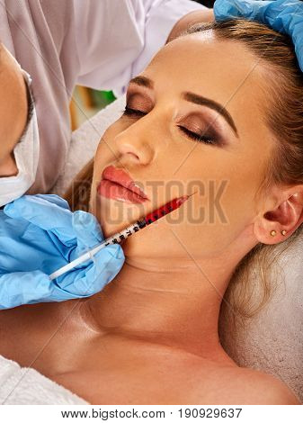 Filler injection for female forehead face. Plastic aesthetic facial surgery in beauty clinic. Beauty woman giving injections. Doctor in medical gloves with red syringe injects cheeks drug.