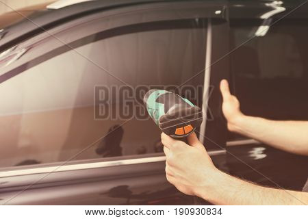 Worker applying tinting foil onto car window