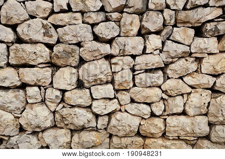 an old stone wall made of loose stone blocks - a natural rock mosaic like pattern