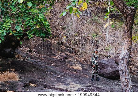 Koh Chang, Thailand - December 20, 2015: Photo of the forester in camouflage clothes standing on a stone of the Khlong Phlu waterfall Mu Koh Chang National Park, Thailand.