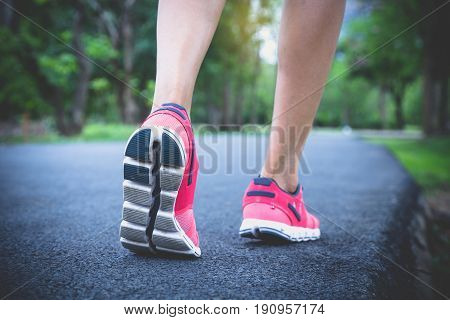 Close up sport woman back view running walking on road in the park.