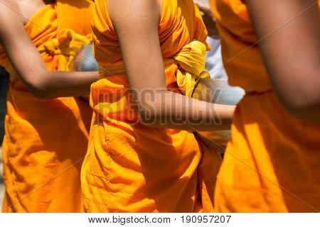 Close up A line of young buddhist monks with alms walkingsfor donation. Thailand traditional culture. faith believe concept.