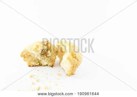Muffin cut in half with scattered crumbs. White background.