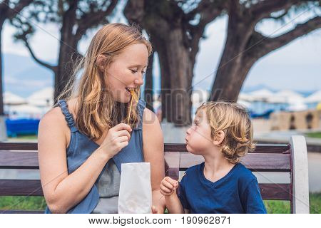 Mom And Son Eat Fried Sweet Potatoes In The Park. Junk Food Concept