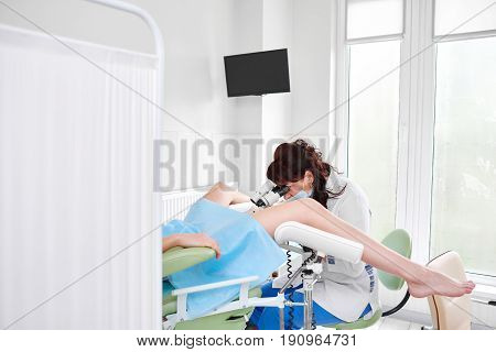 Female gynecologist working at the hospital examining her patient on a gynecological chair. Clinical healthcare feminine concept.