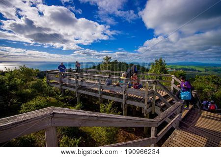 AUCKLAND, NEW ZEALAND- MAY 12, 2017: Unidentified people enjoying the beautiful view from top in the mountain in Rangitoto Island walking in wooden paths, New Zealand in a sunny day.