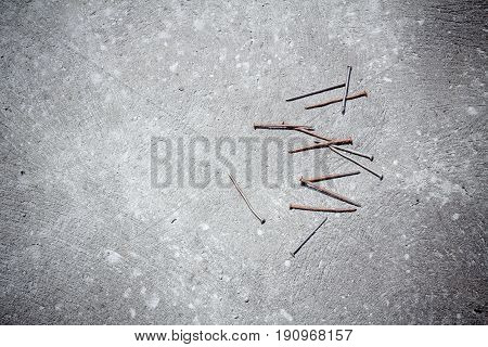 Nails are lying down on clean concrete background.