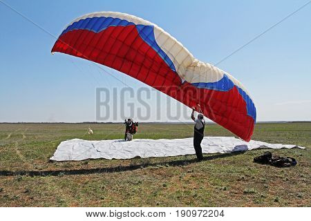 Volgograd Russia - April 20 2013: Assistant helps the paraglider to straighten the paraplane before the flight in Volgograd