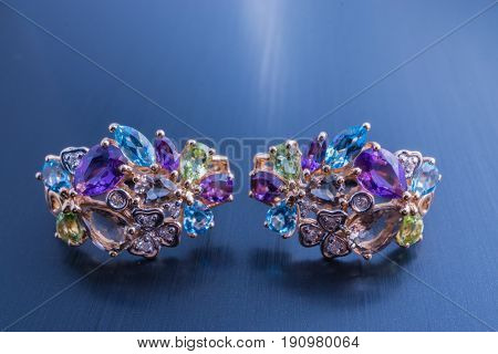 jewelry beautiful pair of gold earrings amethysts apatite peridot sapphires and other gem stones. close up shot on black background