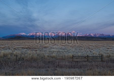 Mountains lit up by the morning sunrise appear as if they are pink and blue