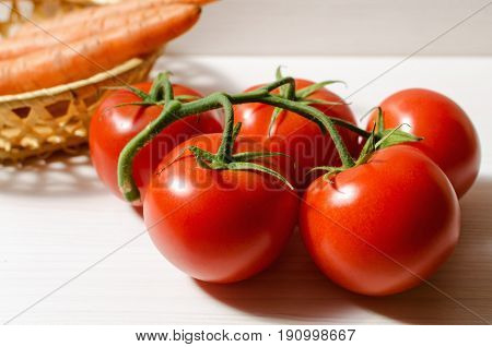 tomatoes and carrots on white wooden table